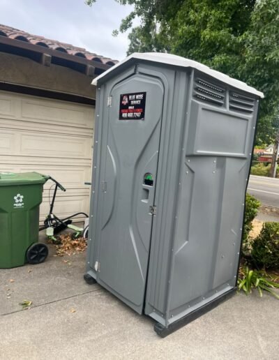 Portable restroom close-up beside a home