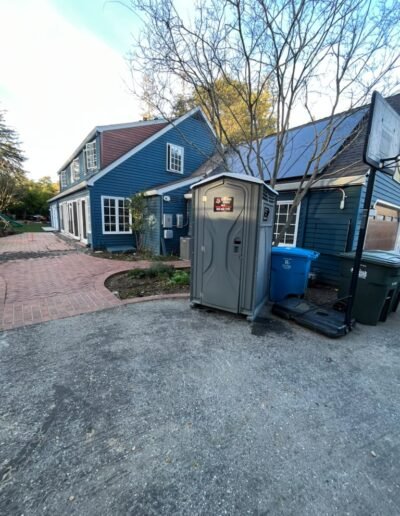 Portable restroom outside a blue house