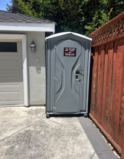 Portable restroom beside a wood fence